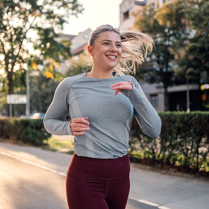 Young sporty woman running in the city during sunset